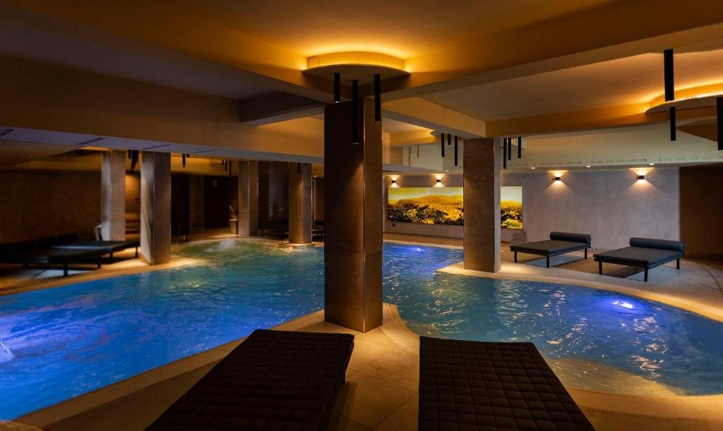 Piscina interna con colonne e lettini relax
