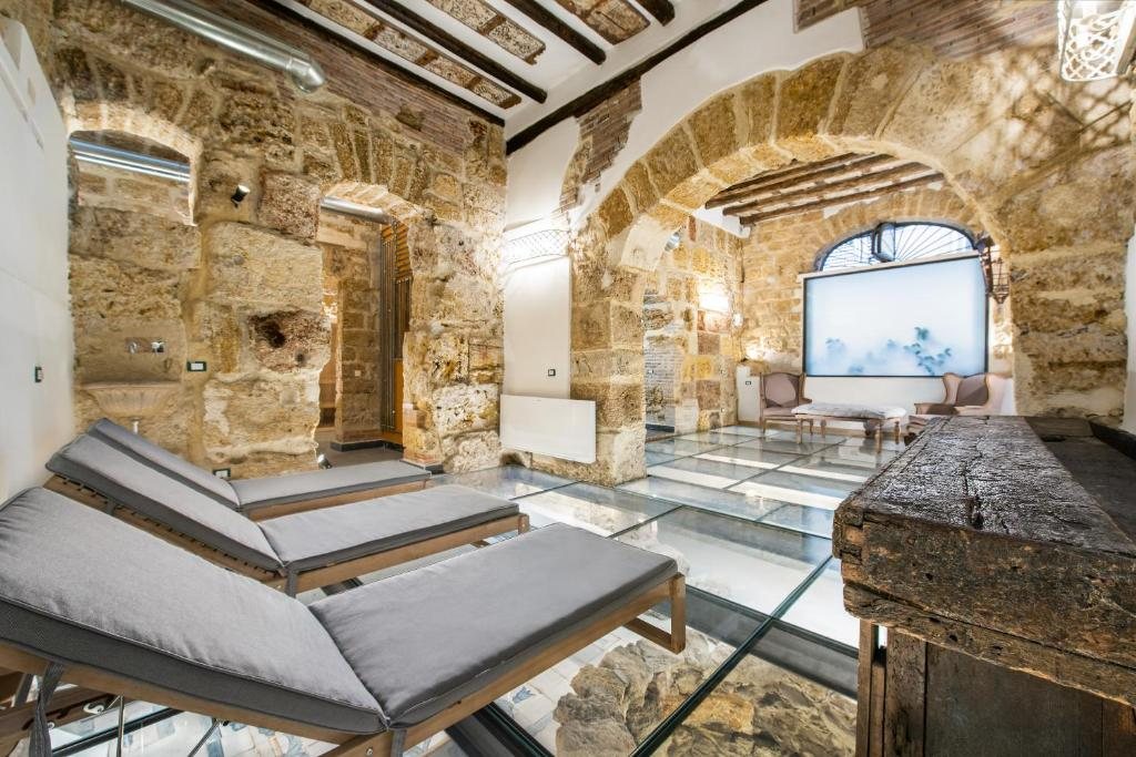 Area relax con lettini, archi in pietra e pavimento in vetro sui resti antichi