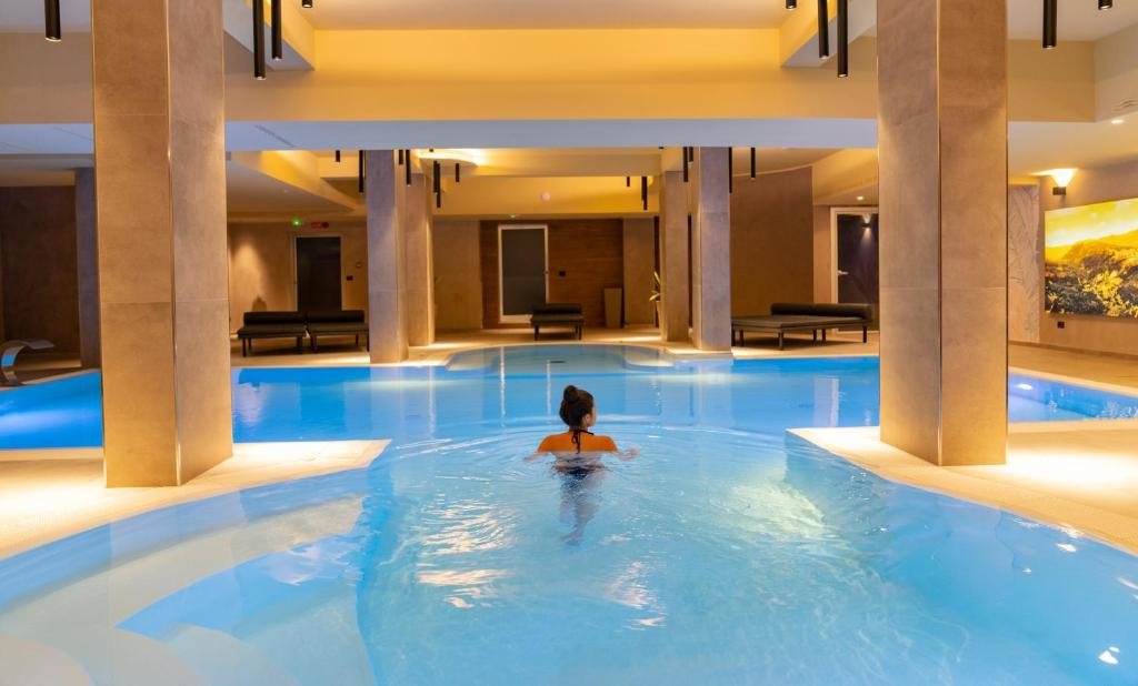 Piscina interna di una spa d'hotel con colonne rivestite in pietra e luci calde