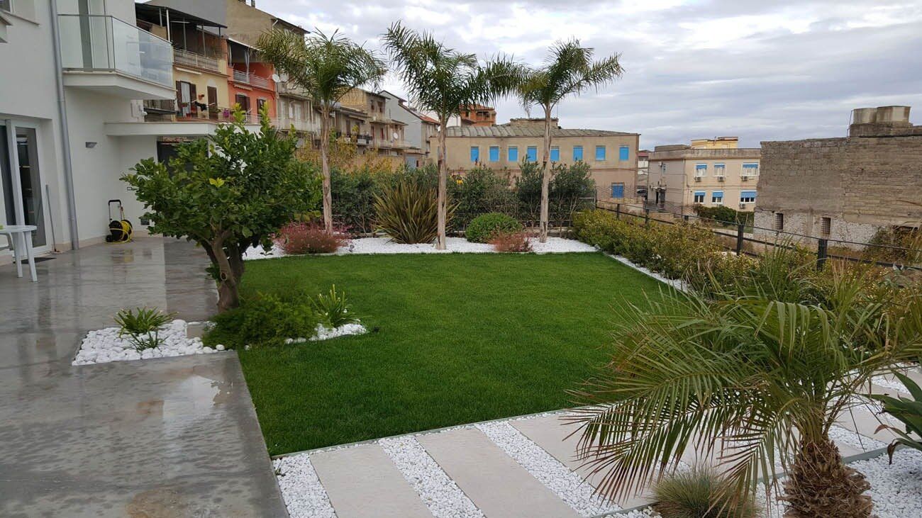 Giardino realizzato con prato, palme e ghiaia bianca