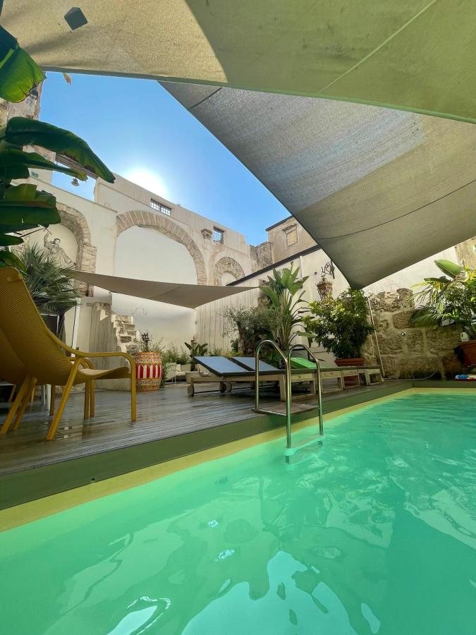 Piscina nella corte con vele ombreggianti e lettini