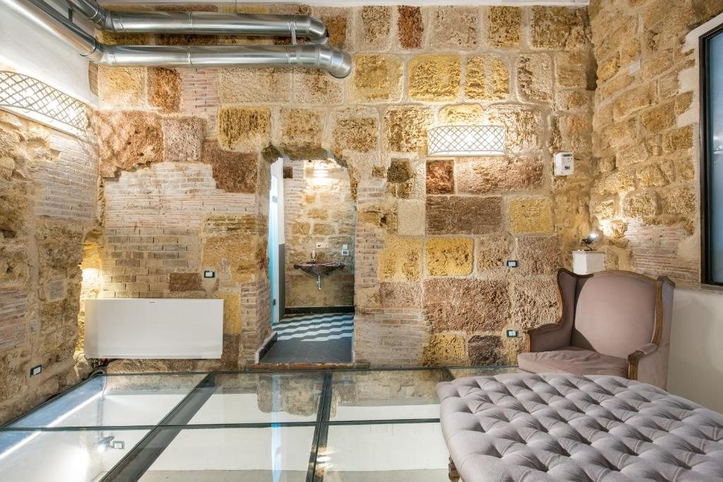 Sala relax con pareti in pietra, poltrona e pavimento in vetro